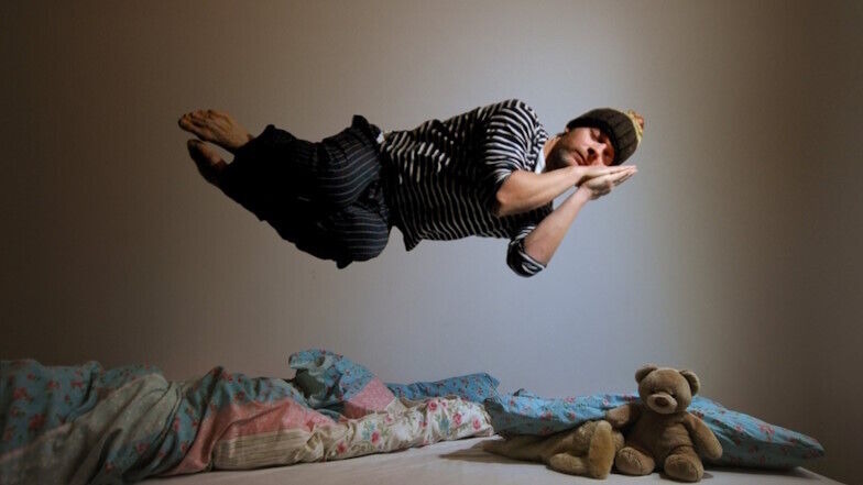 Schlafender Mann schwebt über seinem Bett